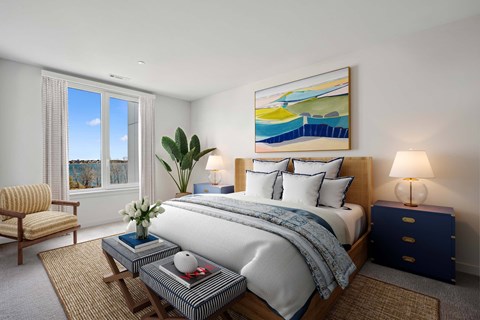 A bedroom with a large bed, a chair, and a painting on the wall.