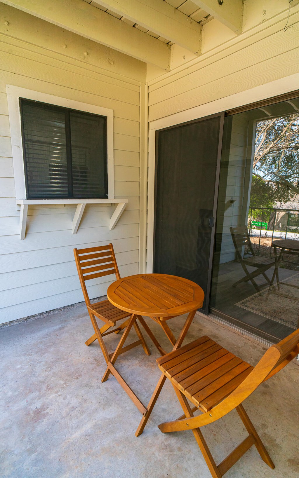 A wooden chair and table are on a patio.