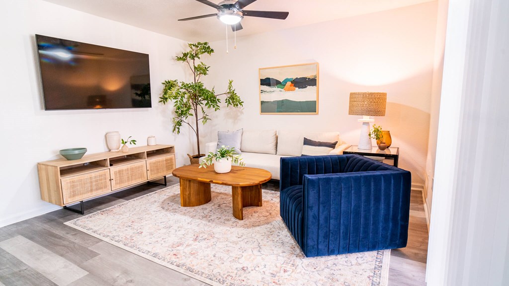 A living room with a blue velvet sofa and a wooden coffee table.