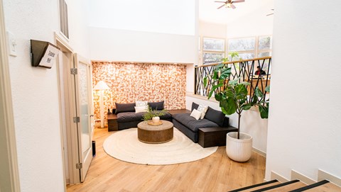 A living room with a black couch and a round wooden coffee table.