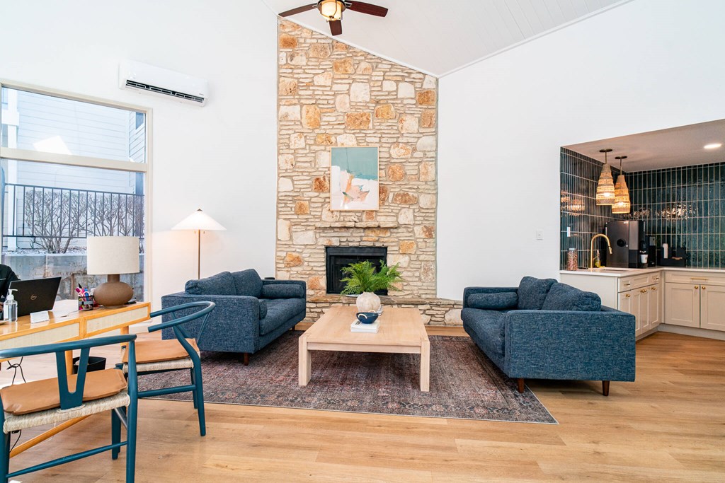 A living room with a stone fireplace and two blue couches.