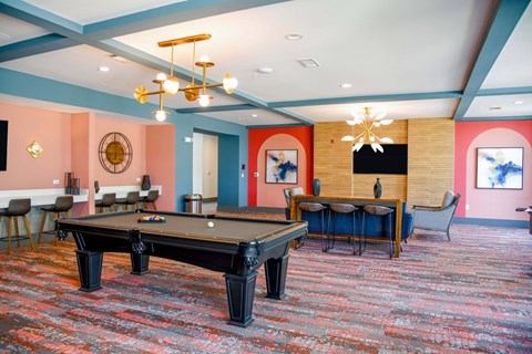 A room with a pool table and a bar area.