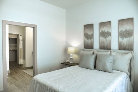 A bedroom with a large bed and three framed pictures on the wall.