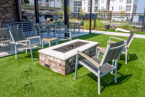 A patio with a fire pit and chairs.
