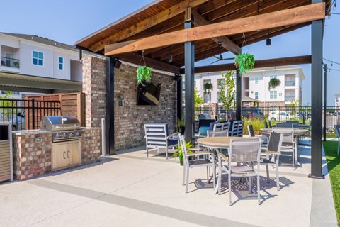 A patio with a table and chairs under a wooden pergola.