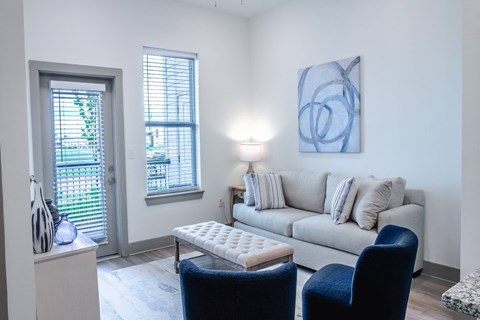 A living room with a couch, chair, and a painting on the wall.