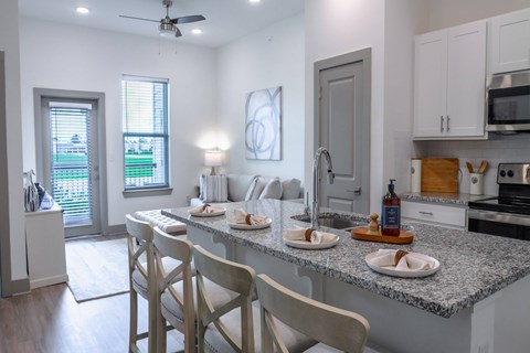 A kitchen with a table set for two with plates and a bottle of wine.