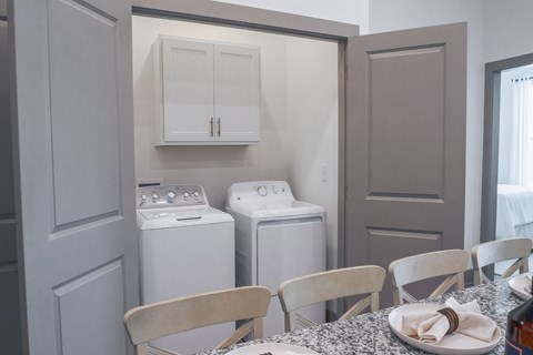 A laundry room with a washer and dryer and a dining room table with chairs.