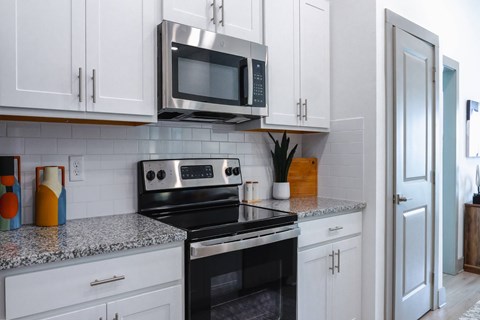 A kitchen with a black stove top oven and a microwave above it.
