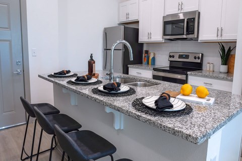 A kitchen with a granite countertop and black bar stools.