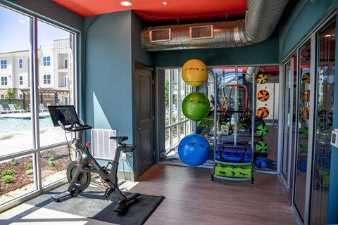 A gym room with a stationary bike and exercise balls.