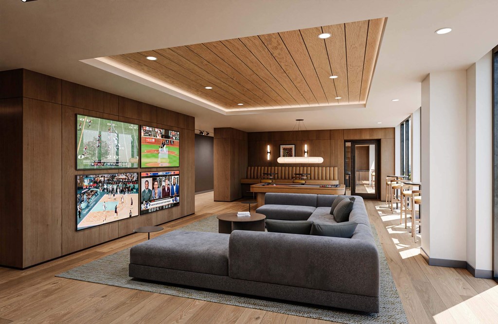A modern living room with a large grey sofa and a TV screen showing multiple sports events.