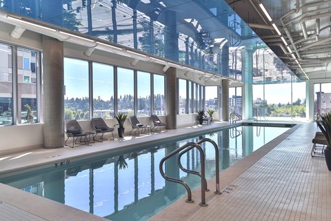 Large indoor swimming pool with a glass ceiling at Soma Towers apartments for rent in Bellevue, WA.