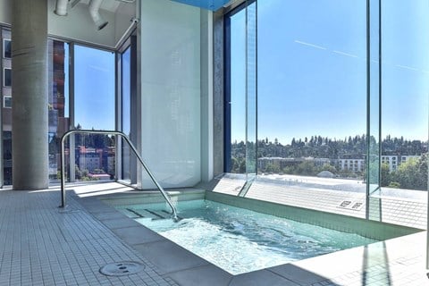 A hot tub is located on a patio with a glass wall.