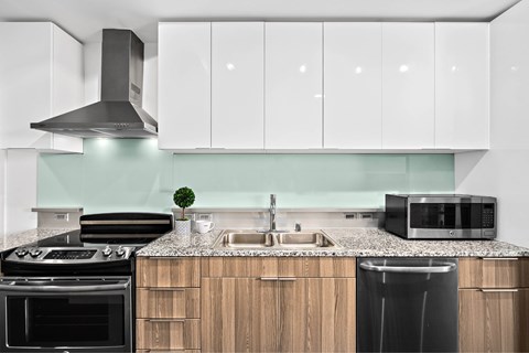 A modern kitchen with a black stove top oven and a black trash can.