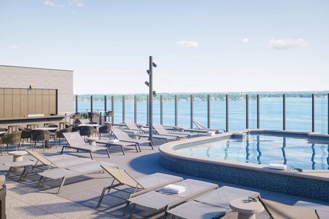 A pool area with sun loungers and a view of the sea.