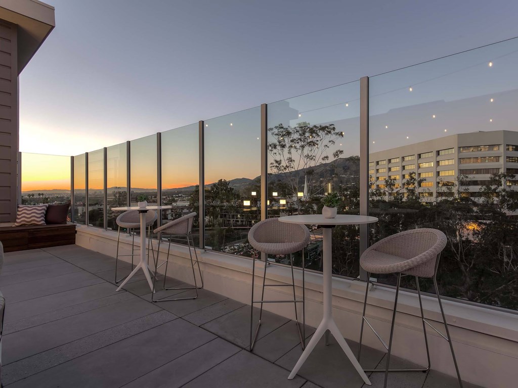 A balcony with a table and chairs overlooking a cityscape at dusk.at The Adeline, Glendale, CA 91203
