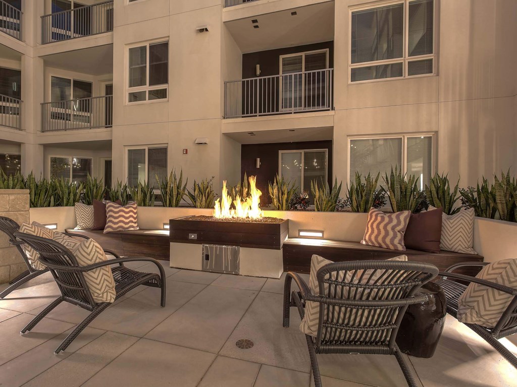 A patio with chairs and a fire pit in front of a building.