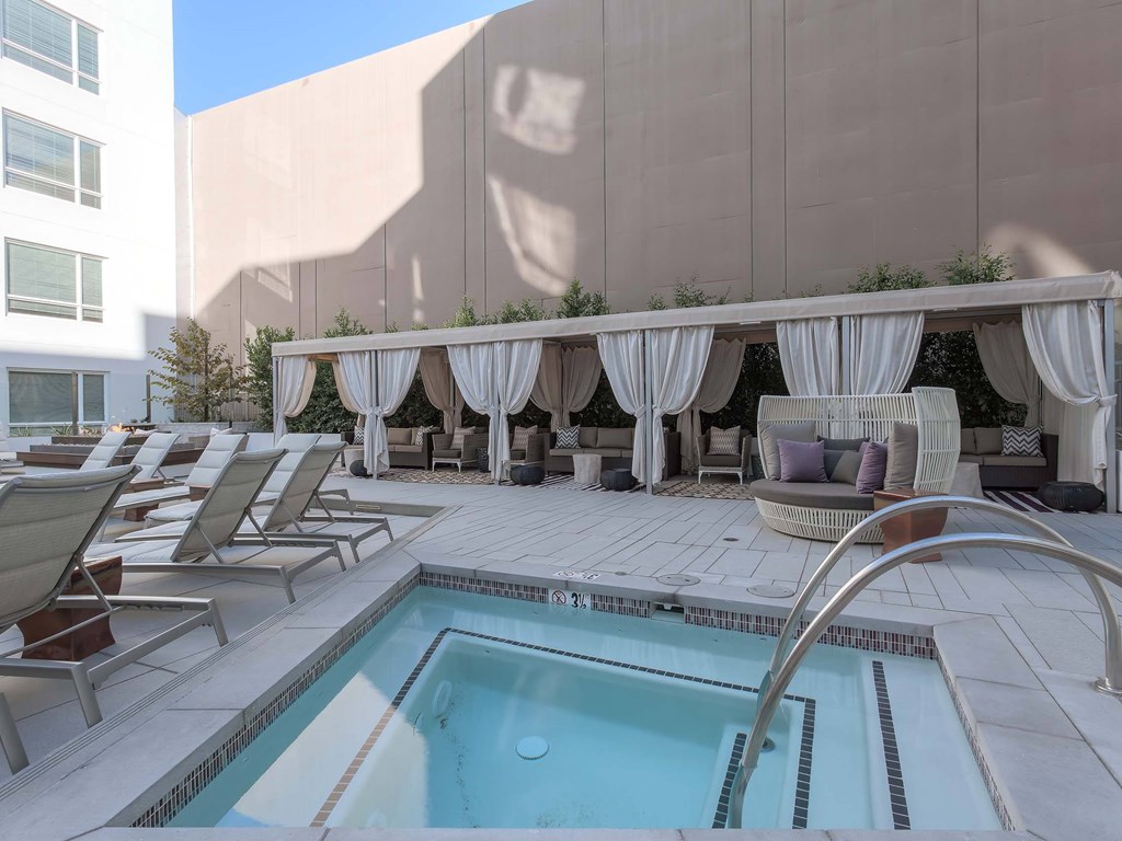 A pool area with a hot tub and lounge chairs.