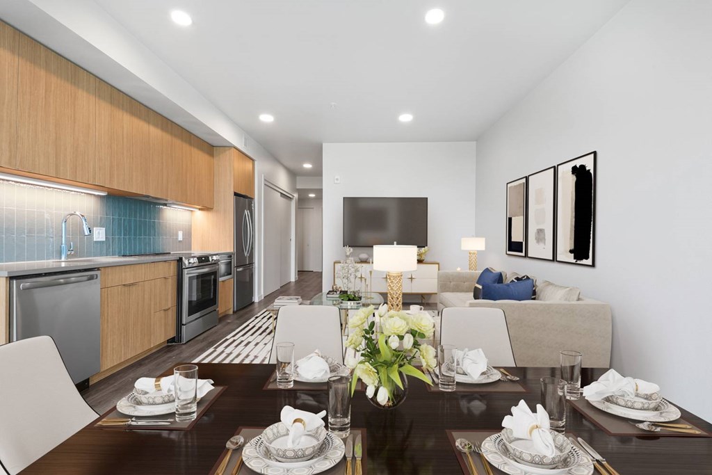 A modern dining room with a wooden table set for two.