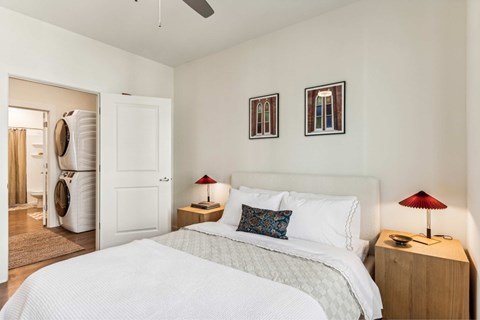 A bedroom with a large bed and two lamps.