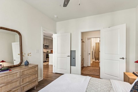 A bedroom with a large bed, a dresser, and a mirror.