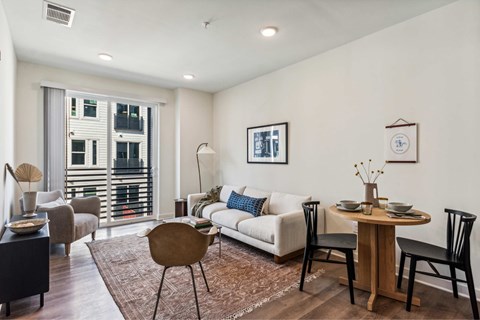 A living room with a white couch, a brown chair, and a wooden table.