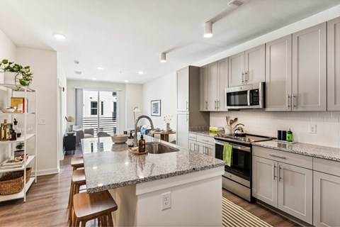 A modern kitchen with a granite countertop and stainless steel appliances.