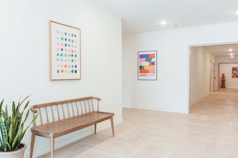 A wooden bench sits in a room with two framed pictures on the wall.