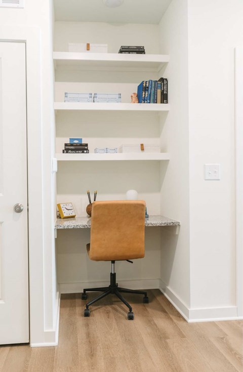 A white desk with a chair and a bookshelf in a room.