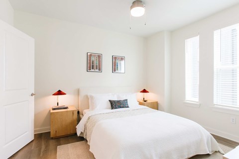 A bedroom with a large bed, two lamps, and pictures on the wall.