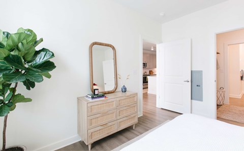 A white room with a wooden dresser and a mirror.