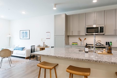 A kitchen with a white sofa and wooden stools.