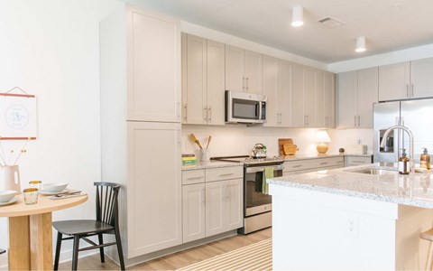 A kitchen with a white counter top and a black chair.