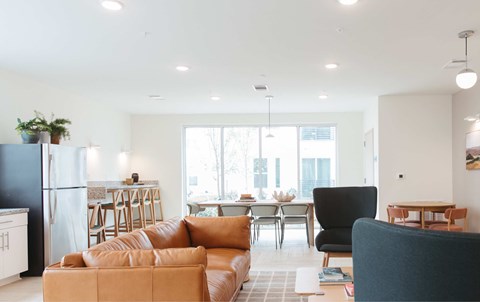 A living room with a black chair and a brown leather couch.