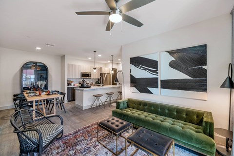 A living room with a green velvet sofa and a dining table with chairs.