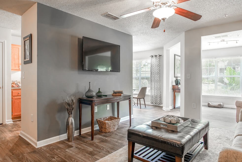 A living room with a grey wall and a flat screen TV mounted on it.at Monterey Village, Jonesboro, GA
