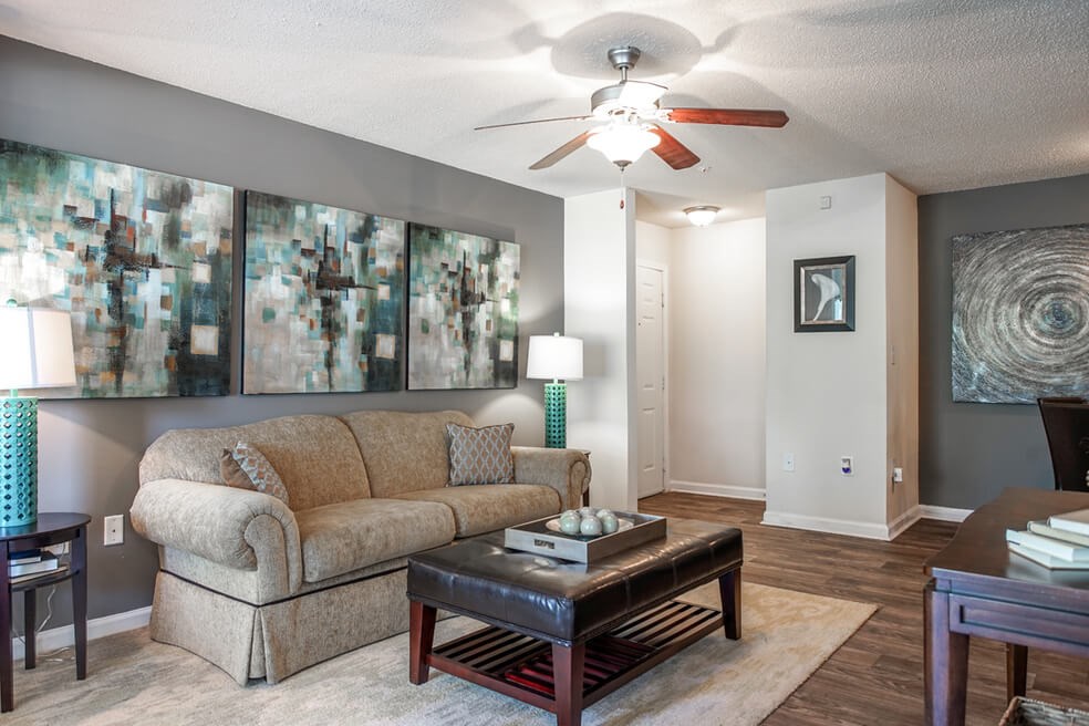 A living room with a beige couch, a coffee table, and a ceiling fan.at Monterey Village, Jonesboro, 30236