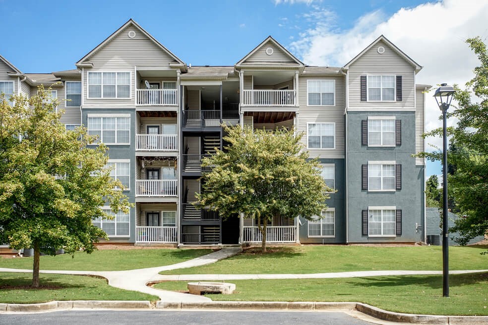 Street-level view of the four story building of Monterey Village Jonesboro apartments for rent.