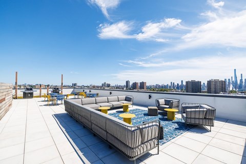 A rooftop patio with a hot tub and chairs.