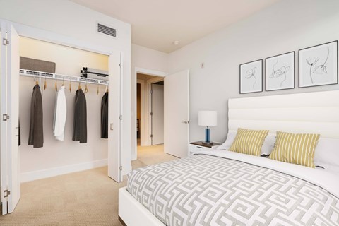 A bedroom with a large bed and a closet with clothes hanging.
