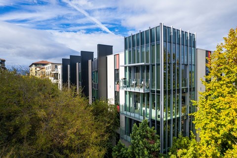 A modern glass building is surrounded by trees.
