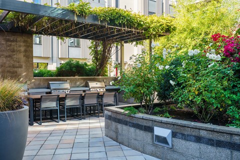 A patio with a table and chairs under a trellis.