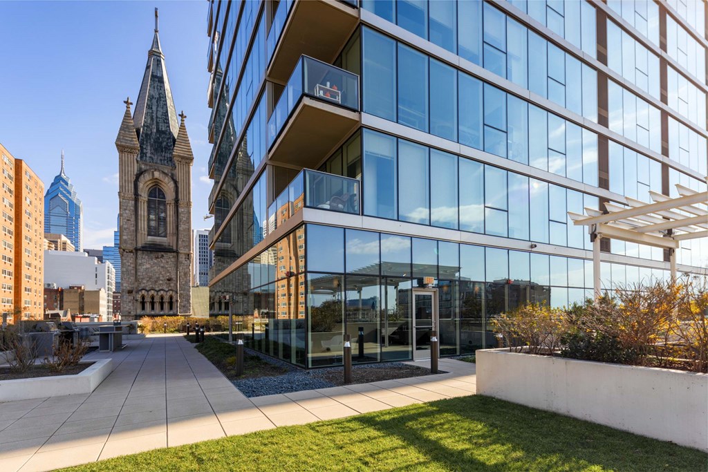 A modern glass building with a clock tower in the background.