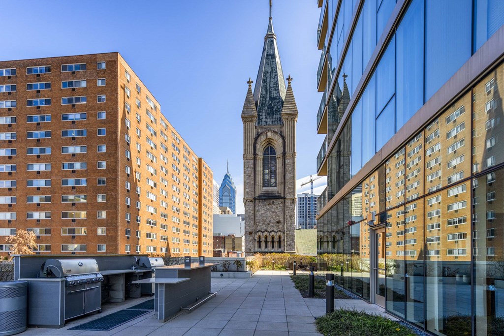 A tall building with a clock tower stands between two modern buildings.