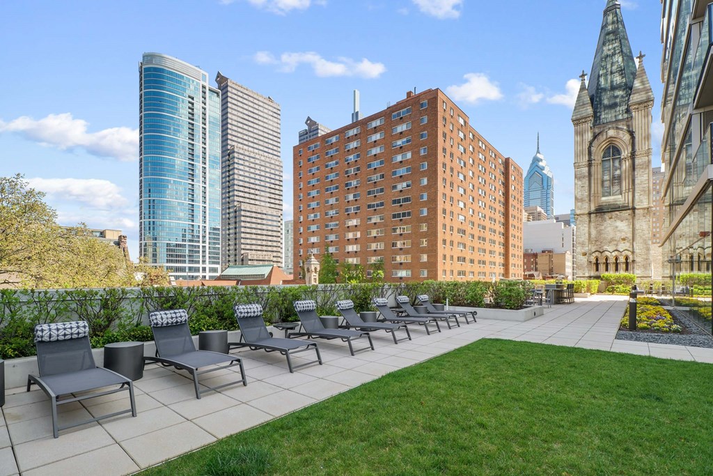 A row of grey chairs are lined up on a concrete patio.