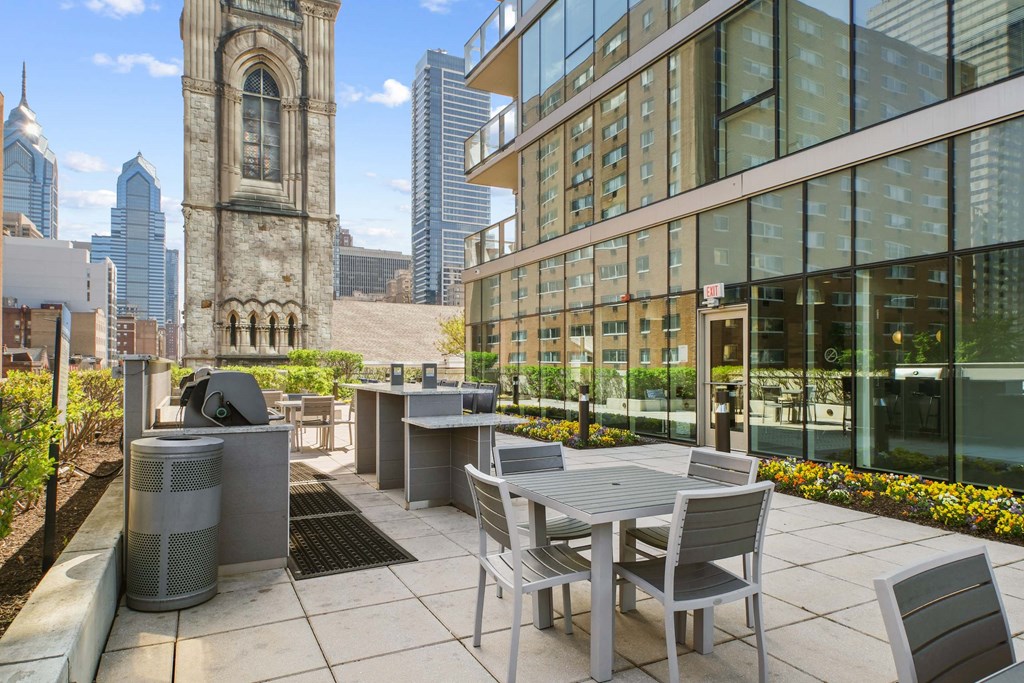 A patio with a table and chairs is in front of a building with a clock tower.