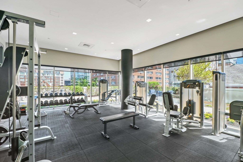 A gym with a variety of equipment including treadmills, weights, and exercise machines.