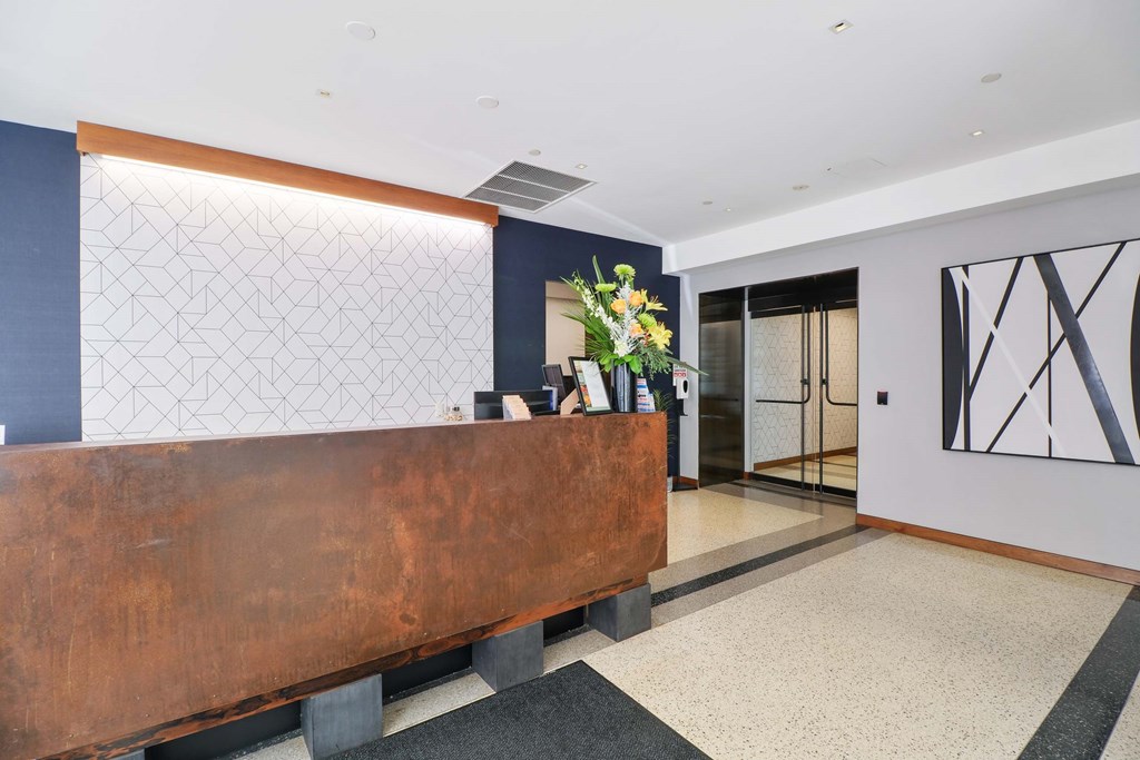 A reception desk with a plant on top and a large abstract painting on the wall.