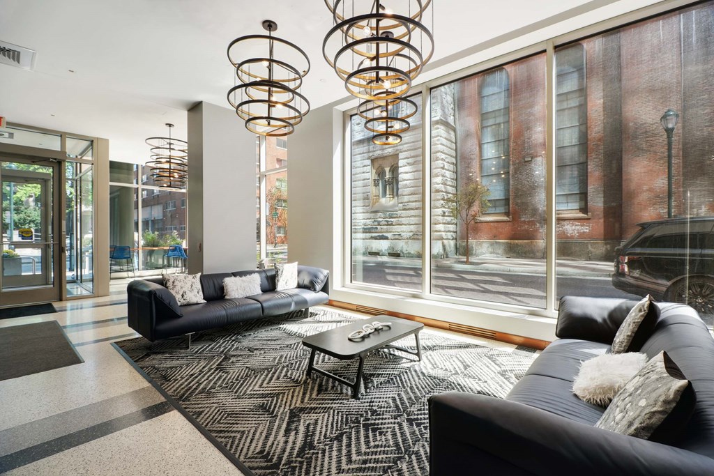 A modern living room with a black couch and a large window.